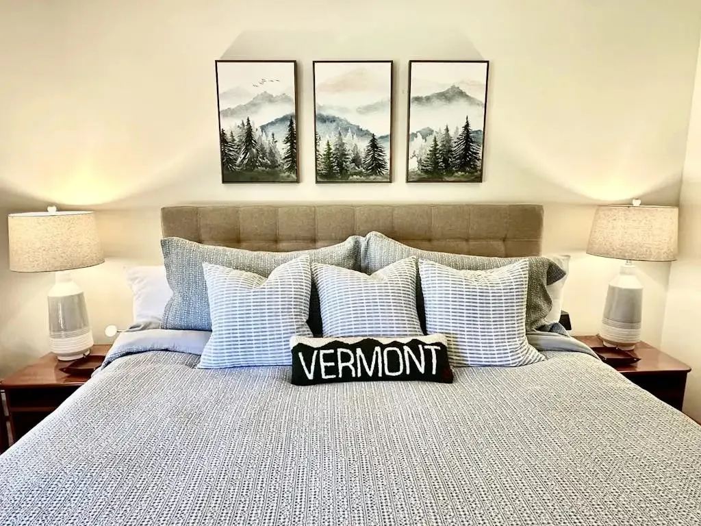 Primary bedroom with a king bed, upholstered headboard, and a triptych of mountain artwork above it