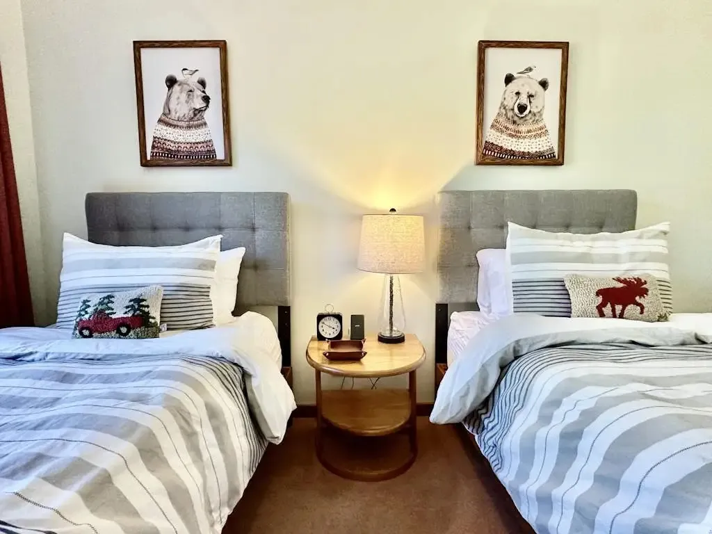 Second bedroom with two twin beds, striped bedding, red curtains, and a mounted TV